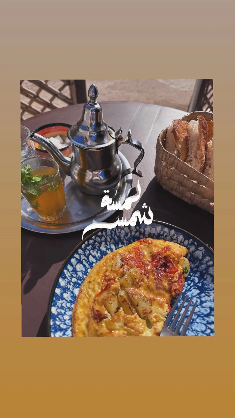 Un thé à la menthe, une théière et une omelette sur une table de terrasse