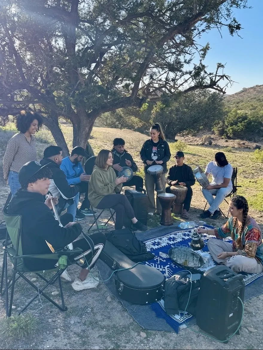 Un cercle d'amis sous un arbre, guitare et derbouka